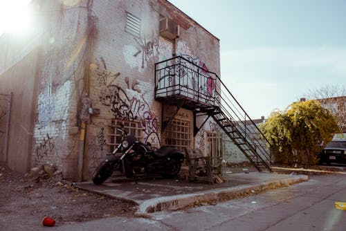 Black Motorcycle Parked Beside Abandoned Building with Graffiti