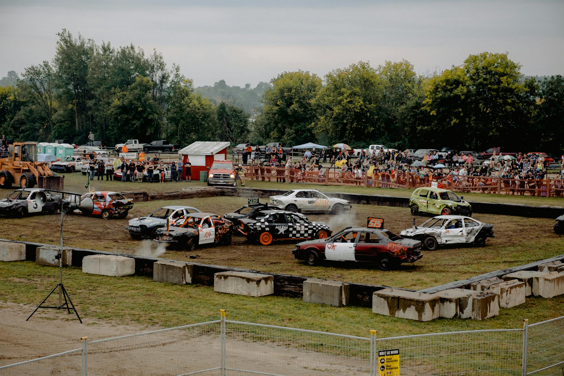 A thrilling demolition derby event with multiple cars crashing in an outdoor arena, watched by a cheering crowd.