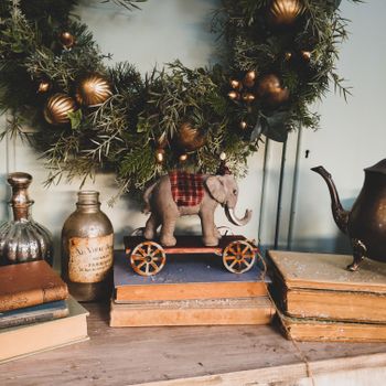 Cozy vintage Christmas setup with a decorative wreath and toy elephant on books.（イメージ）