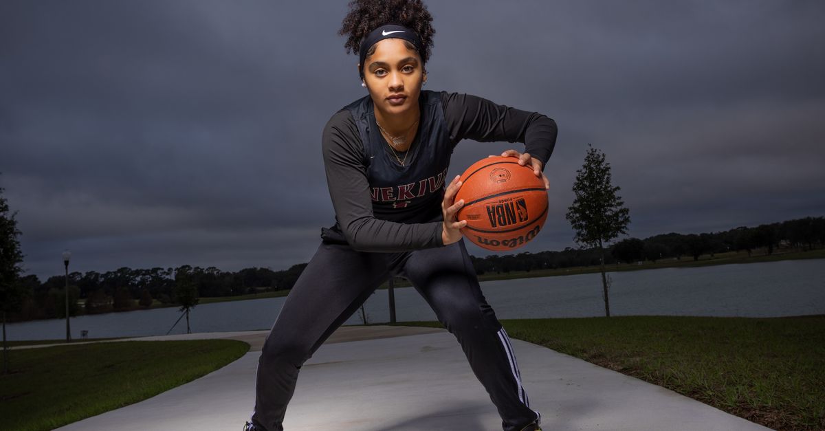 An athletic woman poses with a basketball, showcasing readiness and skill on an outdoor court.