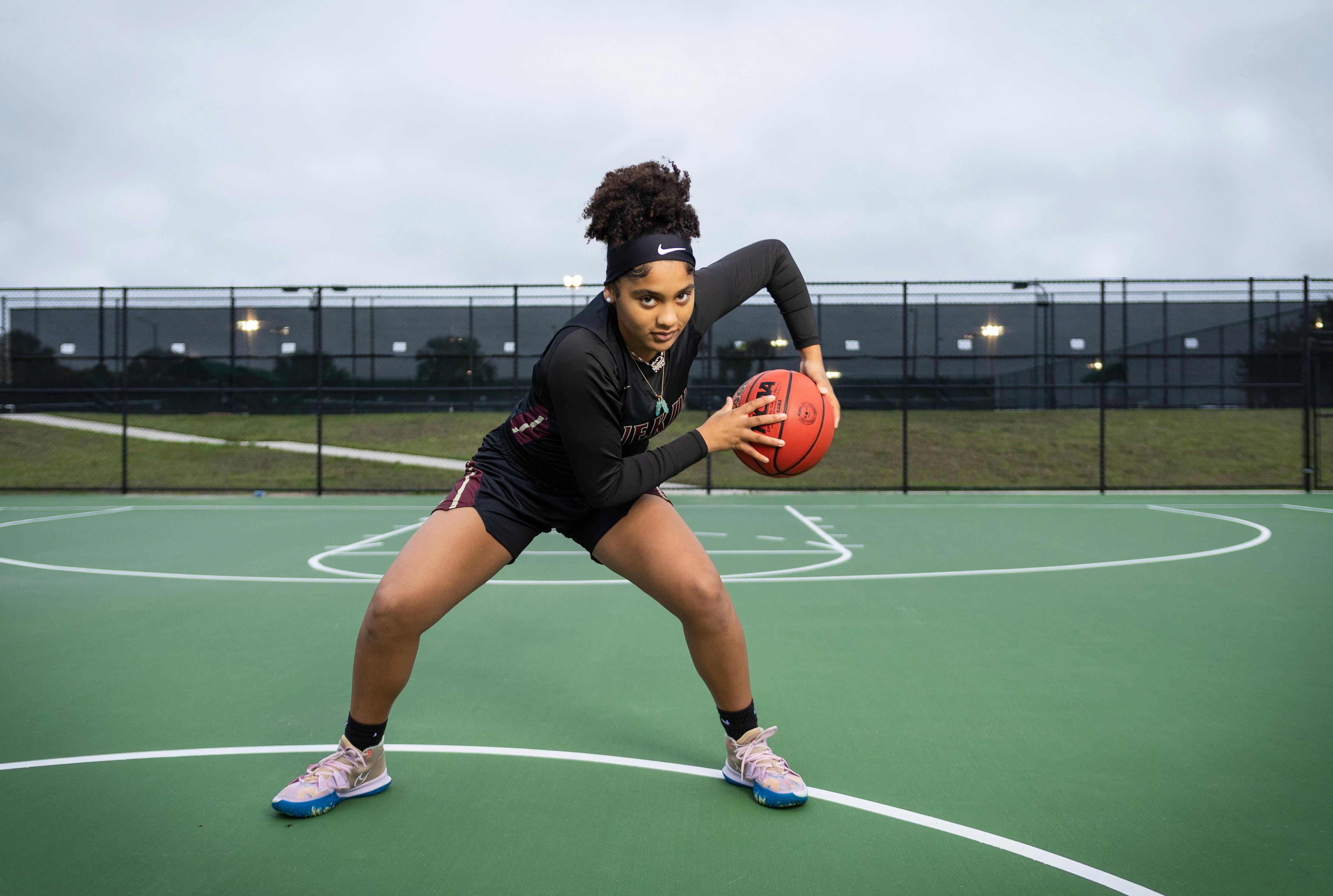 dental and vision insurance plans Florida - Dynamic portrait of a young woman playing basketball on an outdoor court.