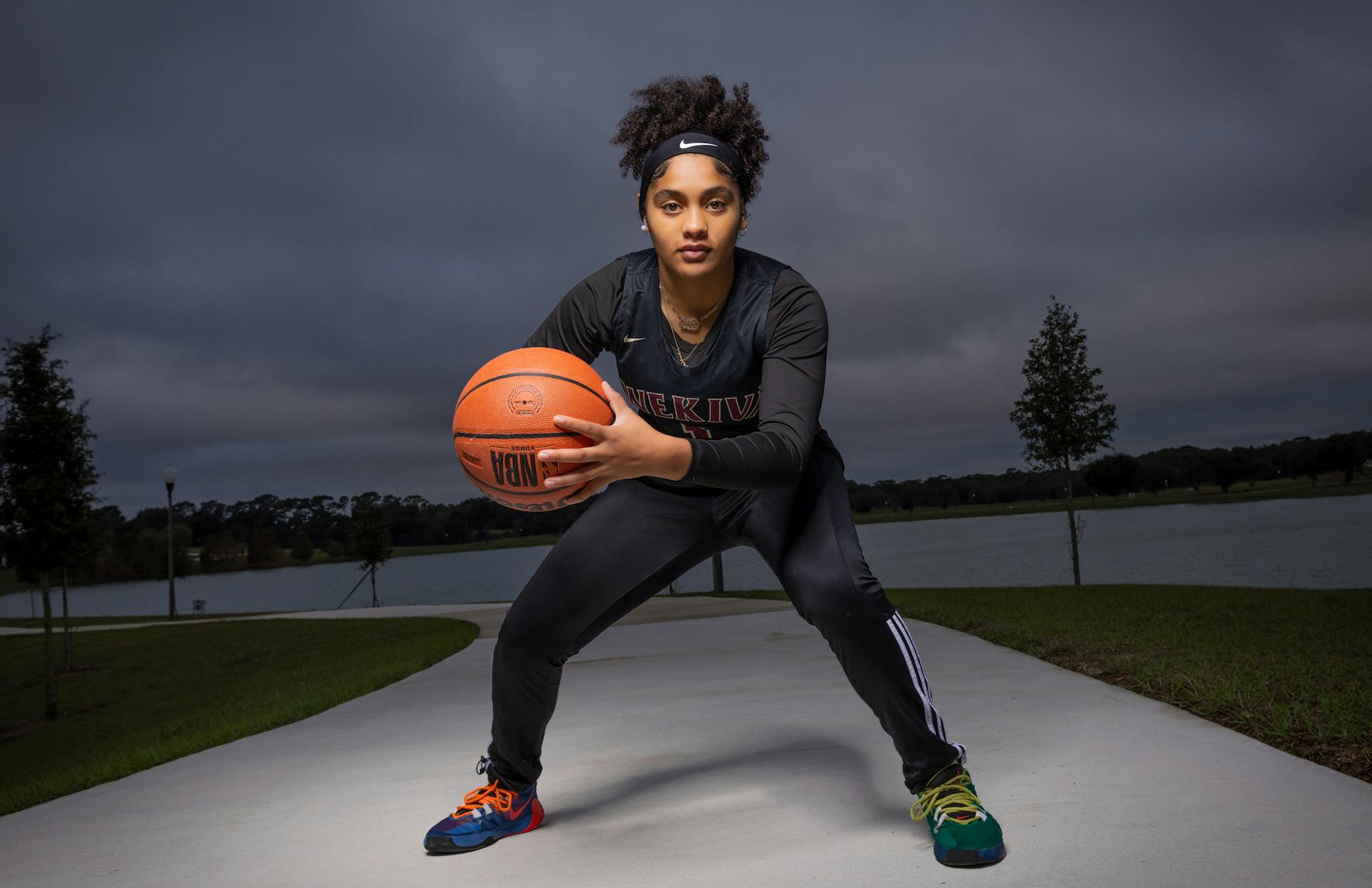 Teen athlete with afro hair holding basketball outdoors in Apopka, FL.