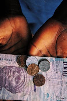 Close-up of hands holding diverse coins and a currency note, symbolizing financial management.