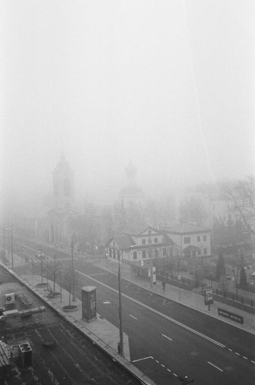 Grayscale Photo of City Covered with Thick Fog 