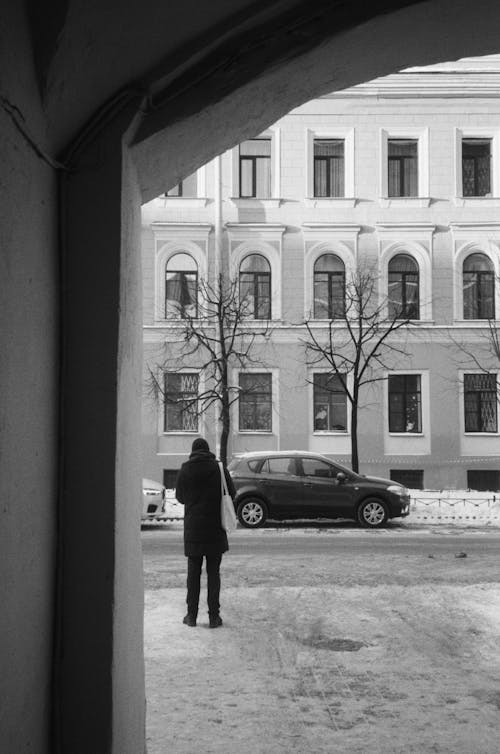 A Grayscale Photo of a Person Standing Near the Car