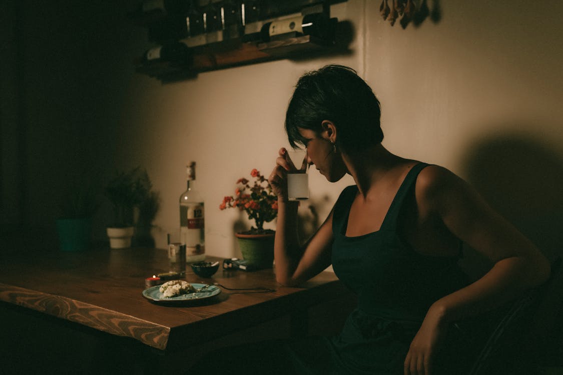 Free Lonely Woman leaning her Forehead ona Glass sitting on Tableside  Stock Photo