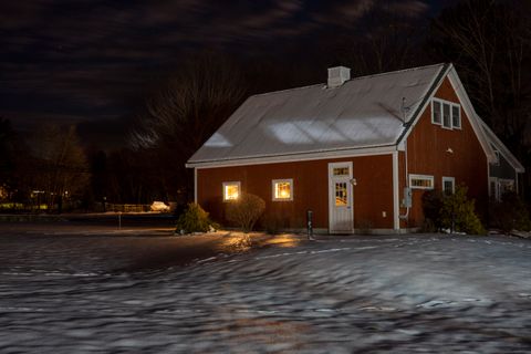 Snow-covered house with warm glowing windows on a winter night