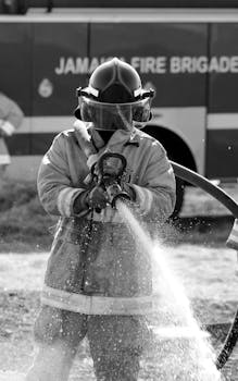 Firefighter in protective gear using a hose, showcasing safety and readiness.