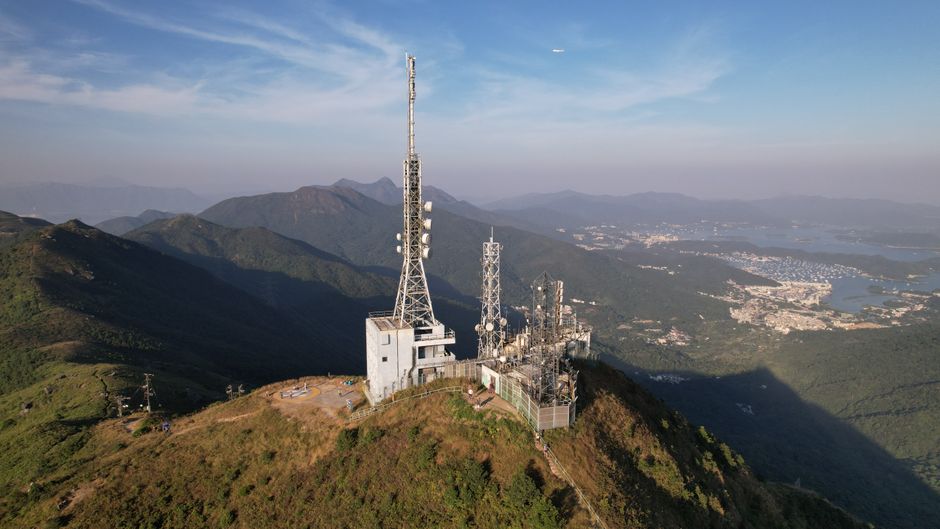 Aerial photograph of a communication tower on a hill in New Territories, Hong Kong with scenic mountain landscape.