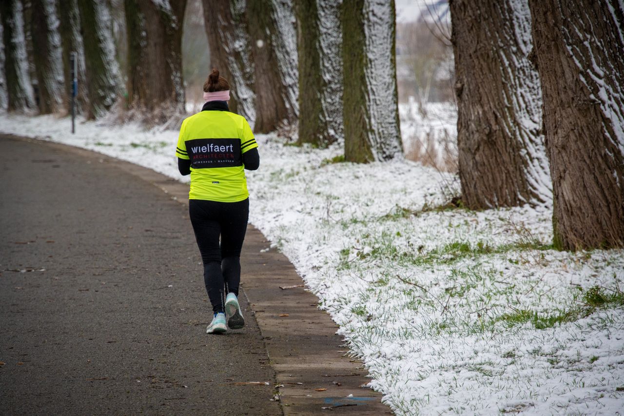 Runner in a neon yellow top and black tights on a snow-lined path