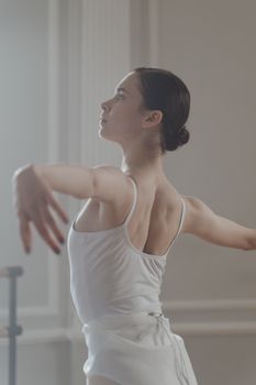Captivating side view of a ballerina practicing in a serene ballet studio.