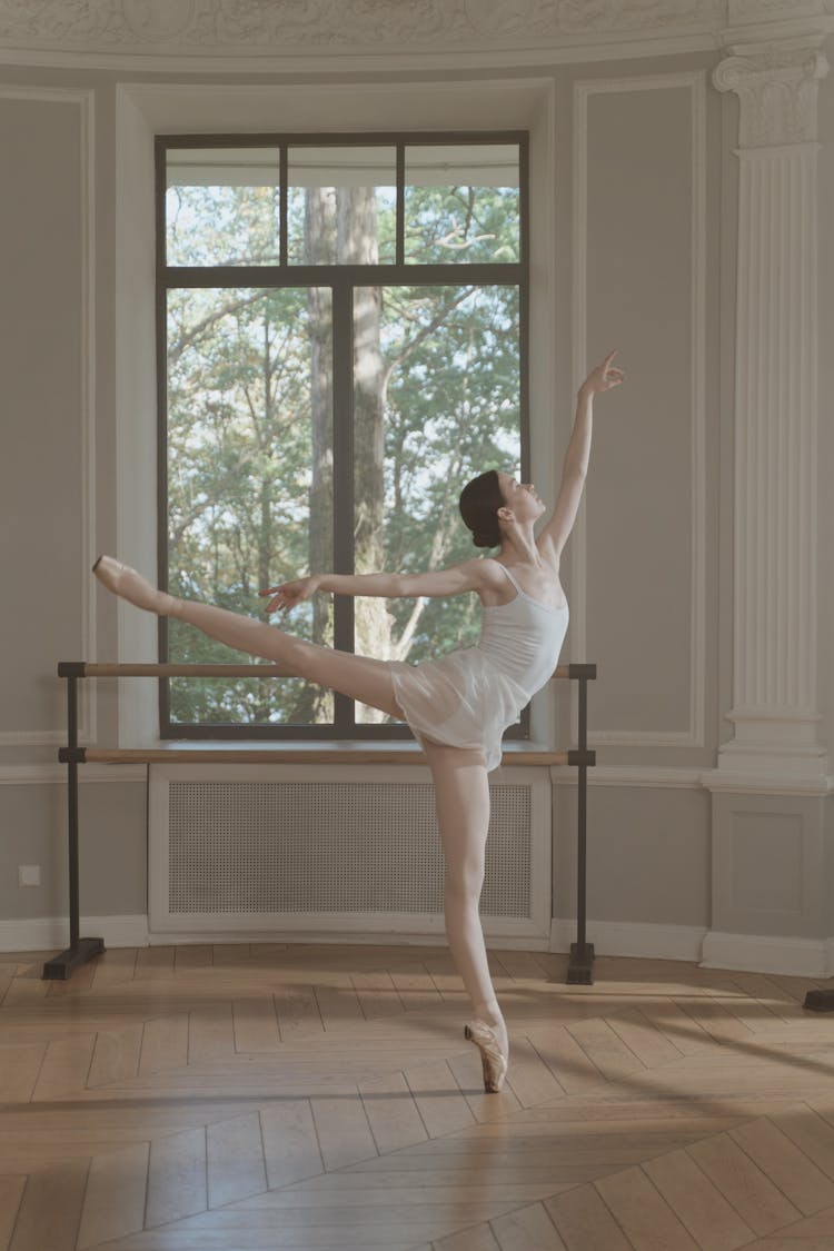 A Ballerina Dancing While Balancing Her Body Using On Leg