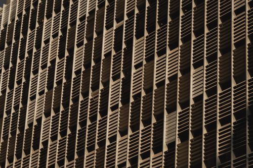 Free Close-up of a modern building facade with geometric patterns and windows. Stock Photo