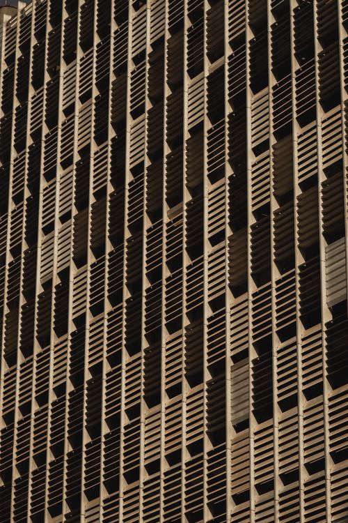 Free Close-up view of a modern building's facade featuring an intricate jalousie design for shadow play and aesthetics. Stock Photo
