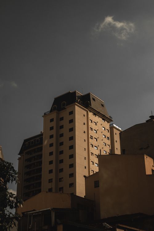 Free Low-angle view of a tall building against a moody sky, showcasing urban architecture. Stock Photo