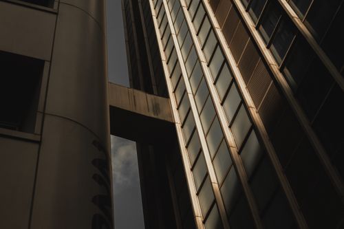 Free Low angle view of a modern skyscraper with geometric glass patterns and dramatic lighting. Stock Photo