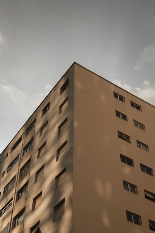 Free Low angle view of a tall apartment building with windows under a clear blue sky. Stock Photo