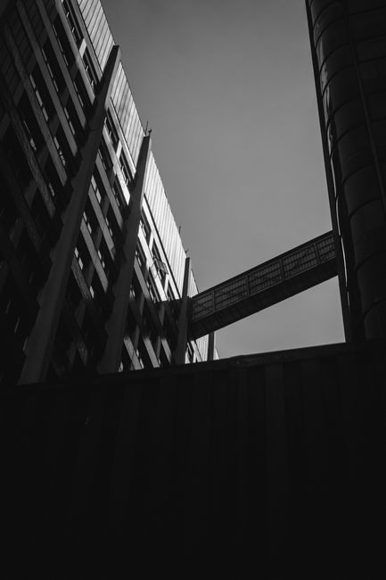 Dramatic low-angle view of modern urban buildings with a connecting bridge.