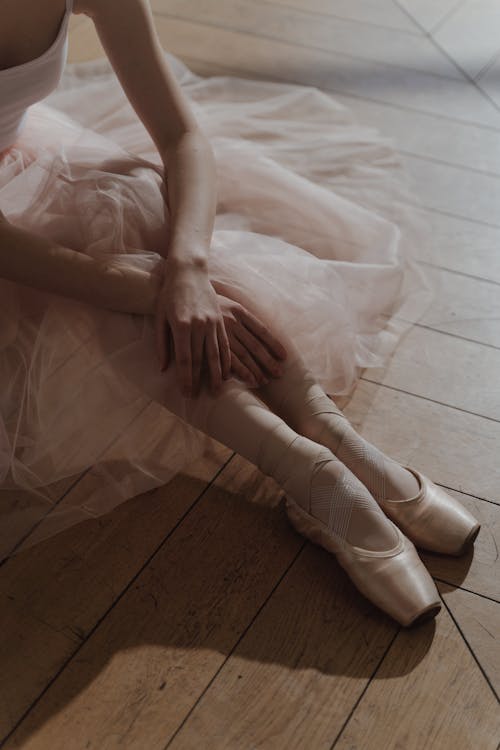 Free Ballerina Sitting on the Floor Wearing Pointe Shoes Stock Photo