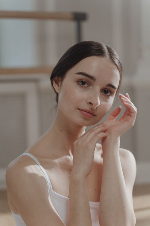 Free An elegant young woman in soft lighting with a serene expression, showcasing natural beauty indoors. Stock Photo