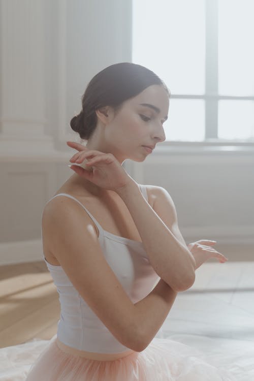 Woman in White Spaghetti Strap and Tulle Sitting on the Floor while Looking Down