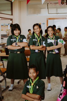 Group of diverse schoolgirls smiling confidently in a classroom setting.