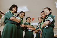 Group of girl scouts smiling confidently indoors, representing teamwork and leadership.
