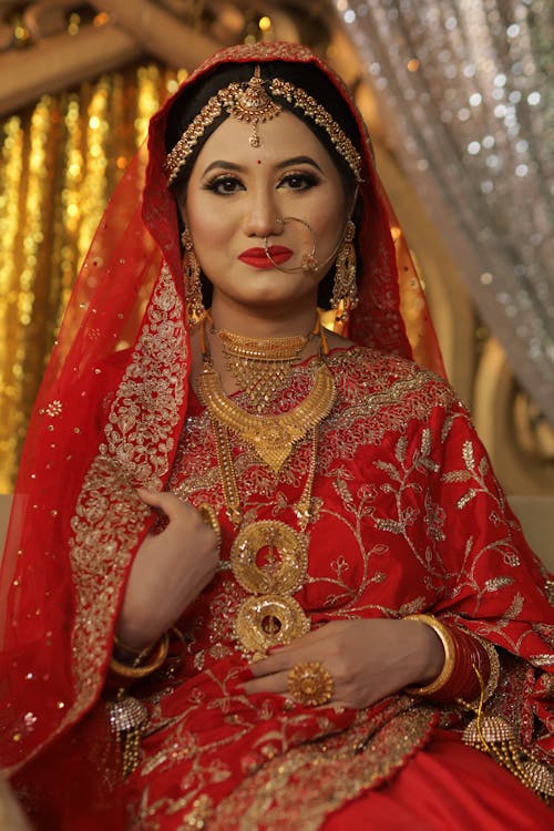 A Woman in Red Saree Wearing Gold Jewelries