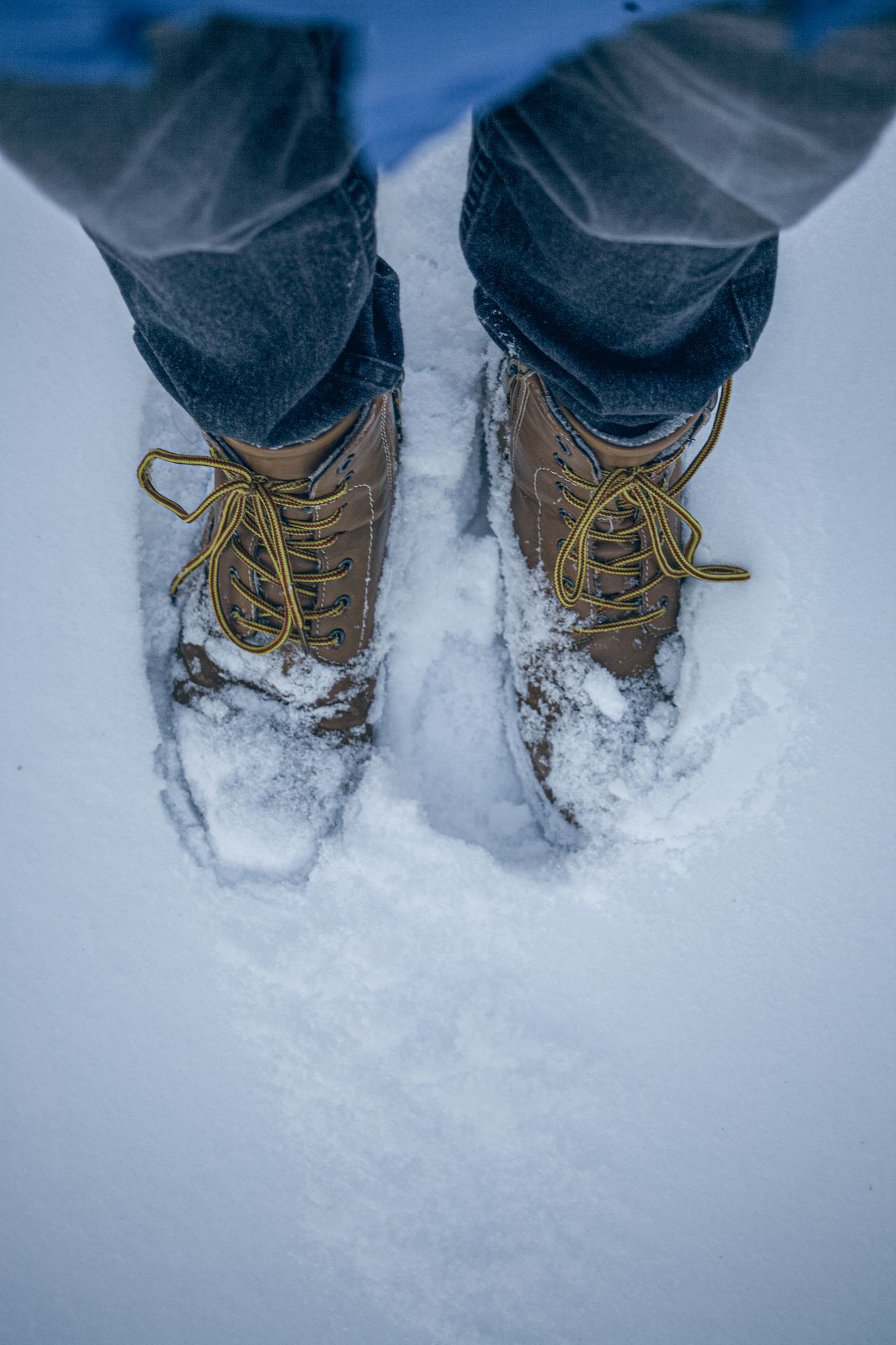 Brown leather lace-up boots stepping through snow