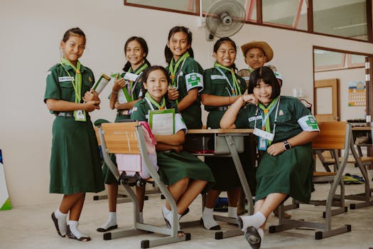 A group of smiling students in uniform posing together in a school classroom.