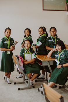 Group of Asian schoolgirls in green uniforms posing in classroom setting. 10637948