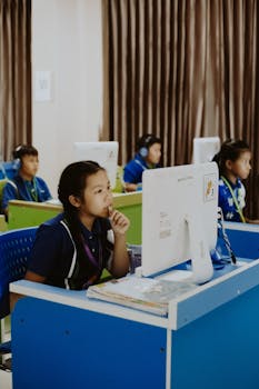 Students focused on computer studies in an educational environment, wearing headphones.
