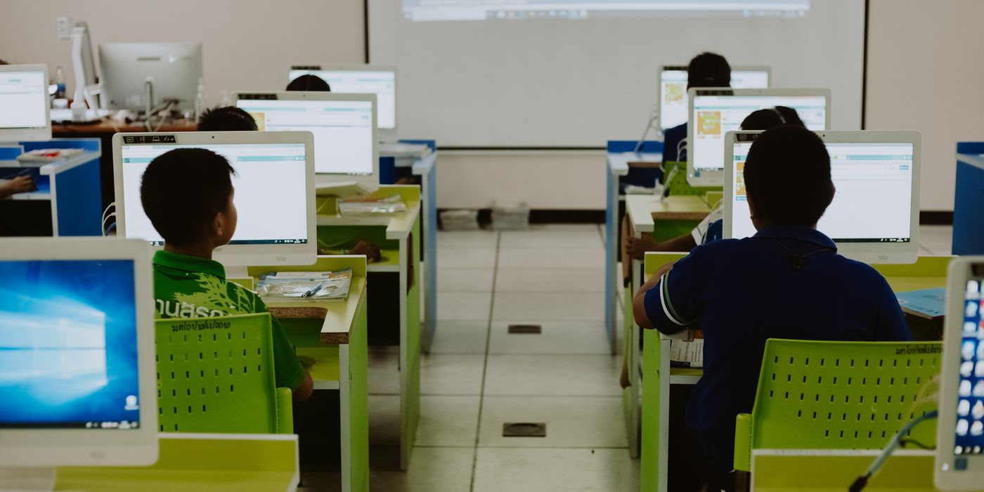 Children focus on computers in a modern classroom setting.