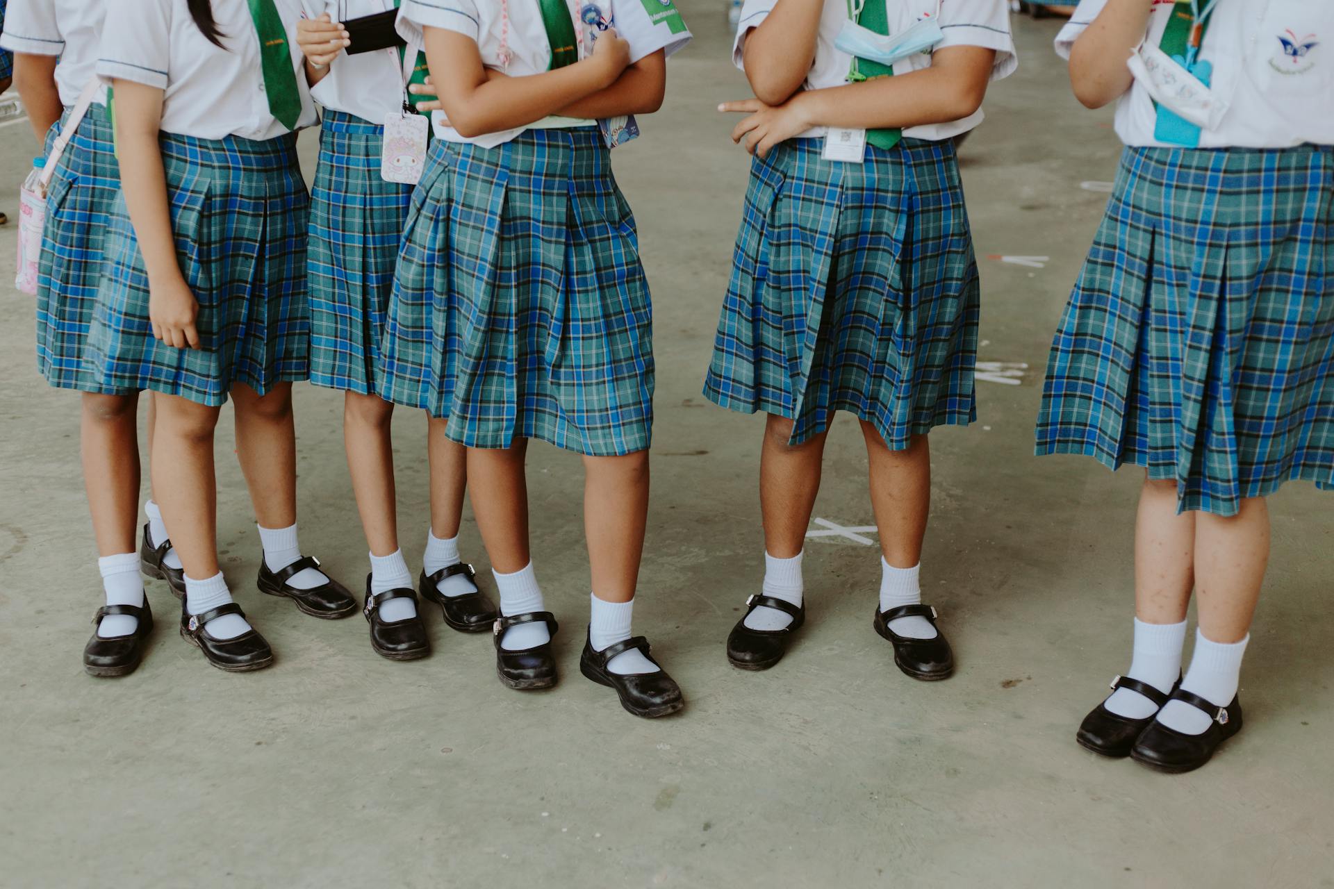 Low Section of Girls in School Uniforms Standing in School Corridor