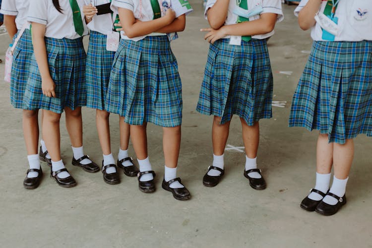 Low Section Of Girls In School Uniforms Standing In School Corridor