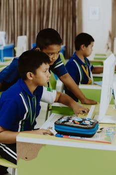 Group of children using computers in a bright, modern classroom.