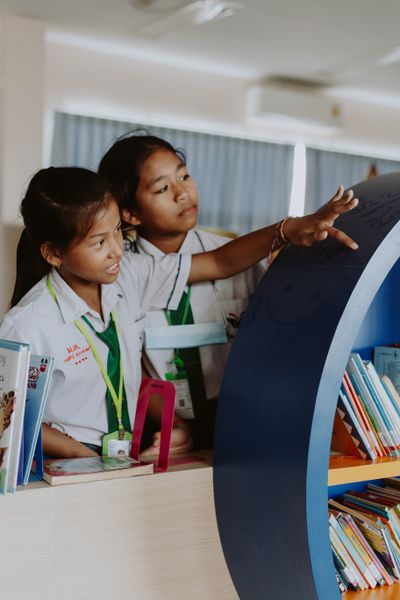 Two young students exploring bookshelves in a library