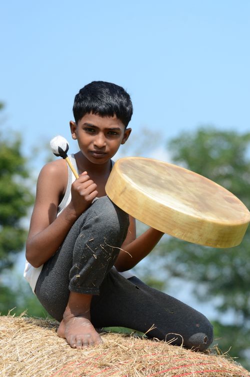 Free Young boy sitting outdoors playing drum on a sunny day in France. Stock Photo