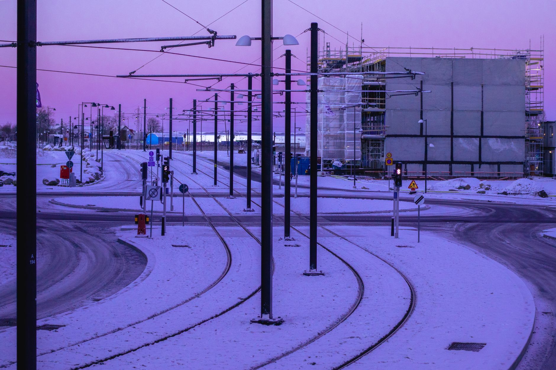 Tram tracks through a snowy construction site at twilight in Sweden.