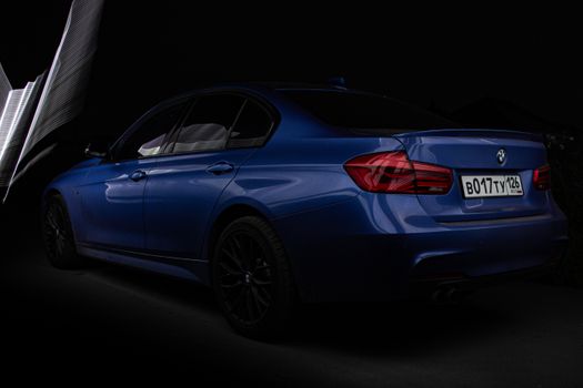 A stylish blue sedan parked in a dark setting, highlighting its sleek design and curves.