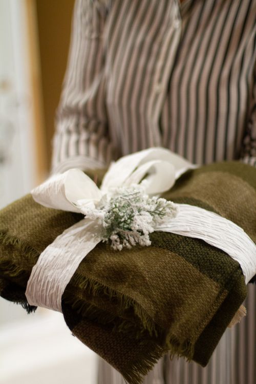 Free A close-up of a green textile gift wrapped with a decorative white ribbon in someone's hands. Stock Photo