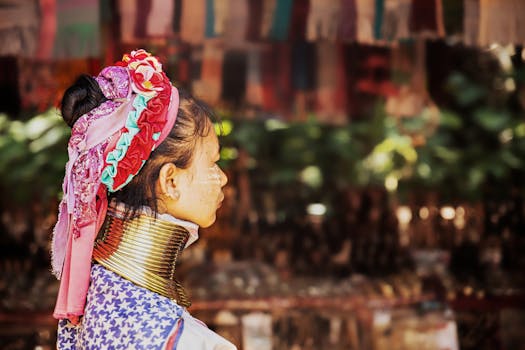 A woman in traditional ethnic attire with neck rings viewed from the side.
