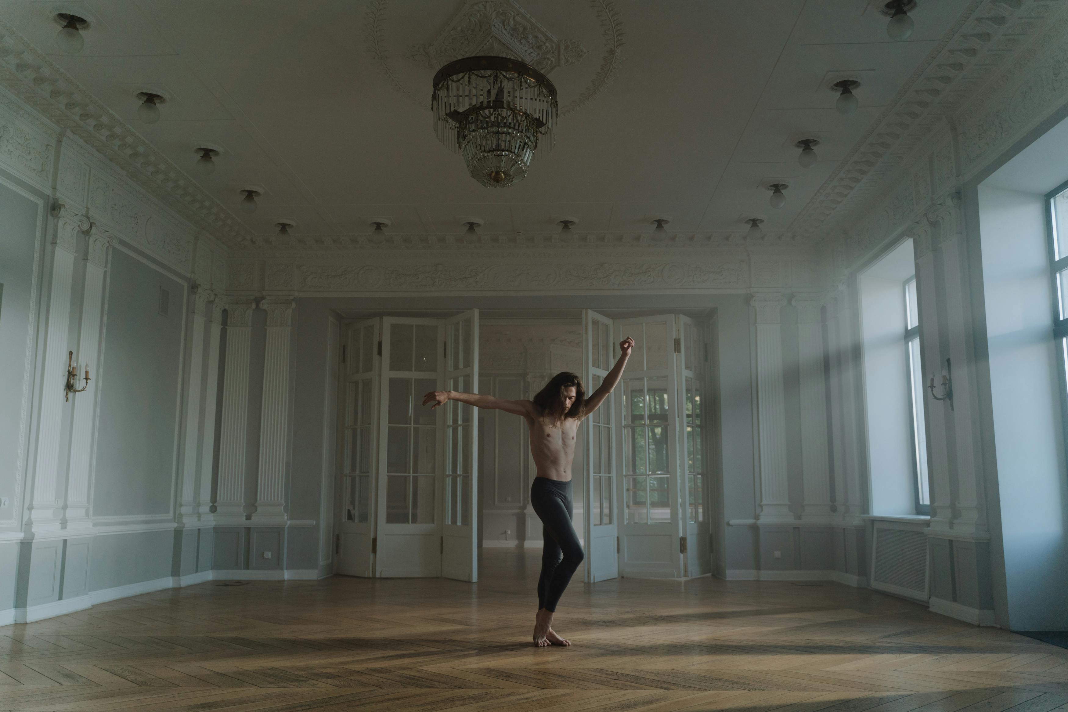 Free A dancer performing ballet alone in a grand, elegant room with natural light. Stock Photo