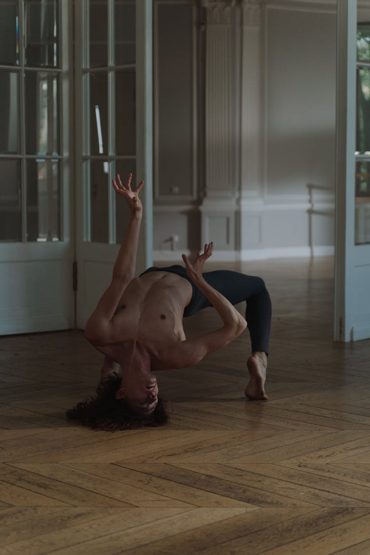 A Topless Man Back Bending While On The Floor