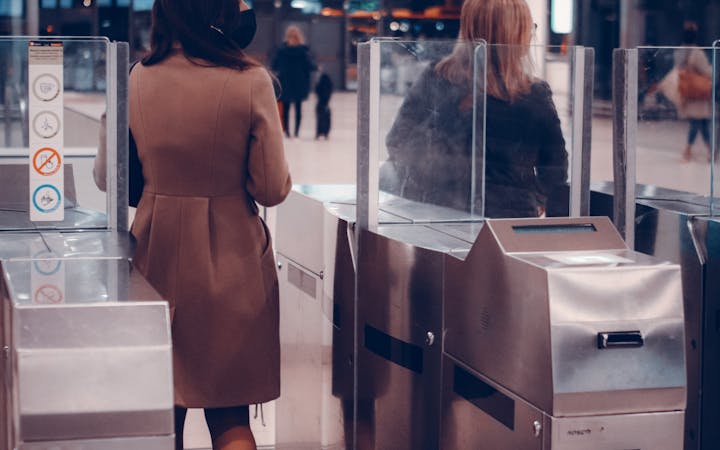 Two women passing through airport security gates, highlighting modern travel.