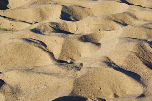 Detailed close-up of sandy dunes with natural light casting shadows outdoors.