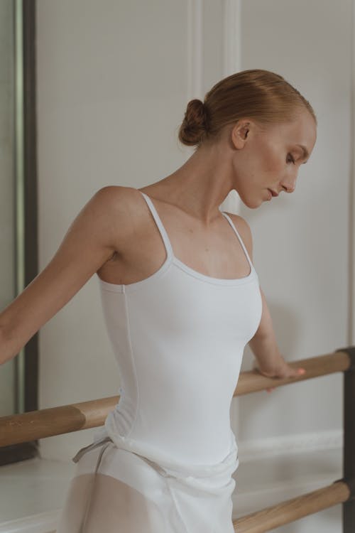 Woman Wearing White Leotard Holding Onto a Metal Railing