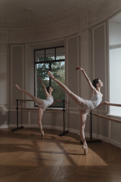 Ballerina in ballet pointe shoes stretches on barre. Woman practicing in  studio Stock Photo by Stock_Holm