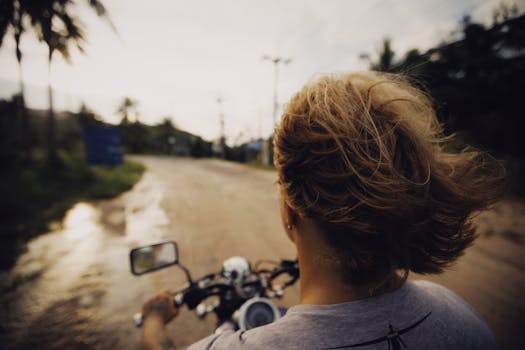 Over the shoulder view of a motorcyclist riding on a rural road at sunset, capturing freedom and adventure.