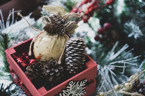Free Close-up of a festive holiday decoration featuring pine cones and ornaments in a wooden box. Stock Photo